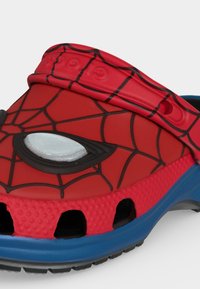 Sabot pour enfants rouge et bleu, stylisé avec un motif de toile noire et un détail blanc sur l'œil, inspiré d'un design de masque de super-héros.