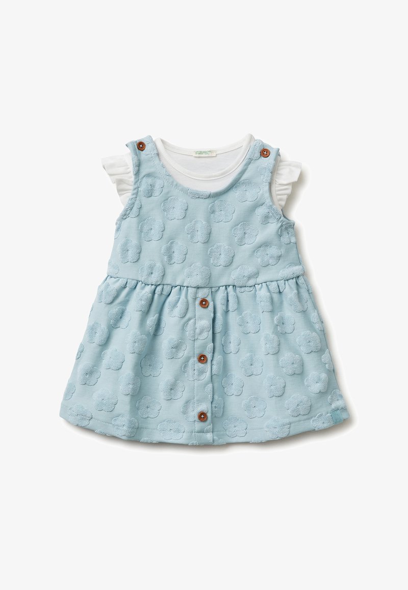 Vestito da bambino azzurro chiaro senza maniche con motivo floreale in rilievo, bottoni marroni sul davanti e camicia bianca a maniche corte con volant sotto.