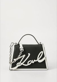 Sort læderhåndtaske med hvid kant og en hvid kursiv "Karl"-logo. Har et håndtag øverst og en skulderrem i sølvkæde.