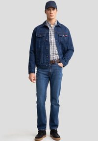 Jeans jakna, karirana srajca, modri kavbojke, črne superge. Jakna ima dve žepu na prsih, obleka pa ima sproščen videz.