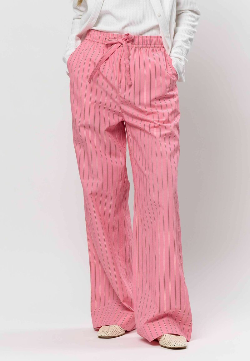 Pantalon ample rose avec des rayures blanches verticales, doté d'une taille élastique et d'un cordon de serrage, fabriqué en tissu léger.