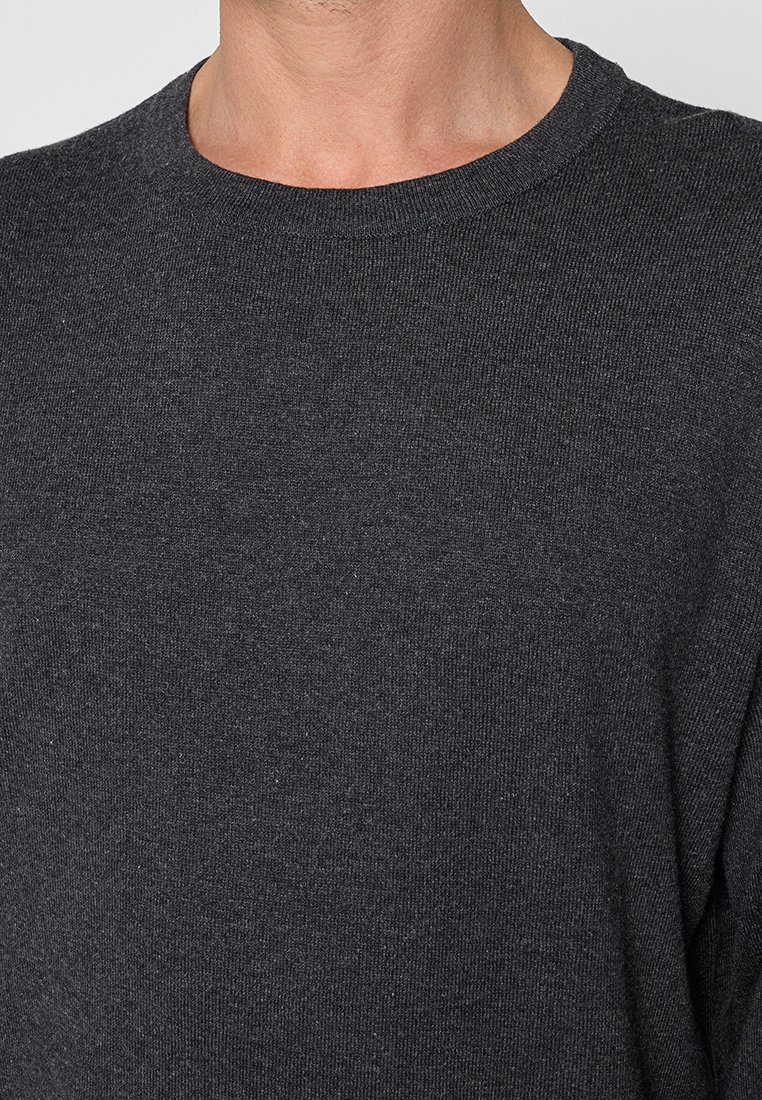 Pull en maille gris foncé avec un col rond et des manches longues, présentant une texture lisse et une silhouette ajustée.