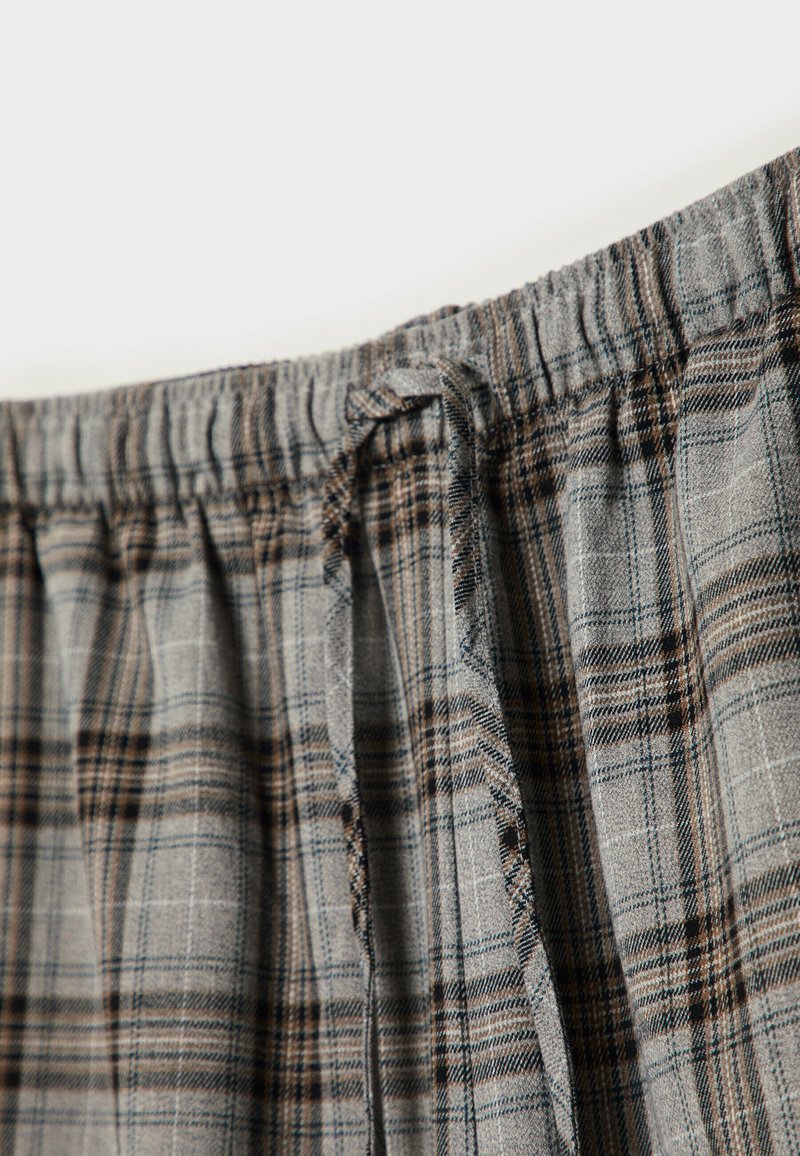 Graues und braunes Karostoff mit einem elastischen Bund und Bindegürtel, der eine weiche Textur und ein feines Karomuster aufweist.