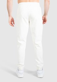 Vita sweatpants med tapered passform, elastisk midjeband och sidofickor. Bärs med vita sneakers som framhäver den minimalistiska designen.