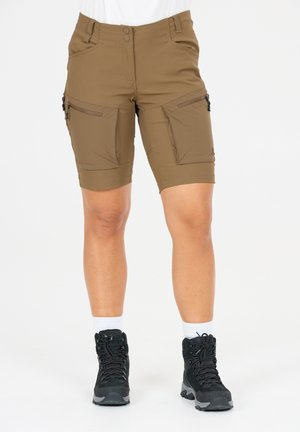Shorts cargo marron jusqu'aux genoux avec poches à fermeture éclair doubles, portés avec des chaussures de randonnée noires et des chaussettes blanches sur une personne debout.