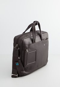 Borsa per laptop in pelle marrone con manici superiori doppi, tracolla rimovibile, scomparti con zip e una tasca frontale a toppa. Finitura testurizzata.