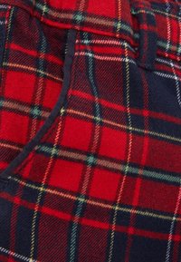 Tessuto a quadri rosso e blu marino con righe alternate di bianco e verde. Texture morbida con un motivo a quadri prominente.