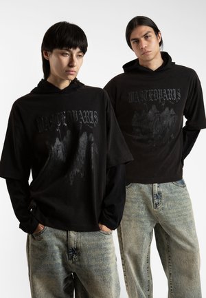 Tricouri cu glugă grafice negre, având textul "WASTED MARS" și un design cu personaje, asociate cu blugi ușor deteriorați de culoare albastră deschisă.