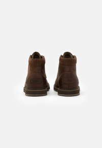 Brown leather ankle boots featuring a smooth finish, rounded toe, and contrasting rubber sole. Back displays a stitched label and minimal accents.