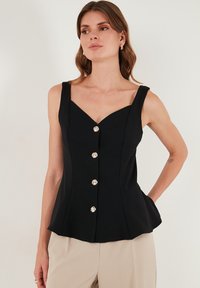Schwarzes ärmelloses Top mit V-Ausschnitt, fünf silberne Knöpfe vorne, taillierter Oberkörper und Peplum-Saum. Glatte Stofftextur.