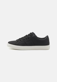 Sneaker sintetiche nere con una superficie liscia, caratterizzate da cuciture minime, suola in gomma bianca e allacciatura frontale. Logo in rilievo sul lato.