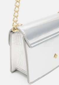 Silver metallic handbag with a textured finish, gold chain strap, and flap closure. Features clean lines and a small gold logo detail.
