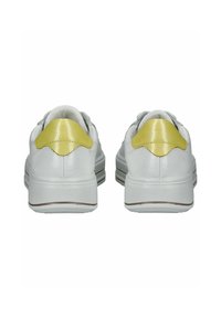 Białe sneakersy o teksturowanej powierzchni, z żółtym akcentem na syntetycznym obcasie i żłobioną gumową podeszwą.