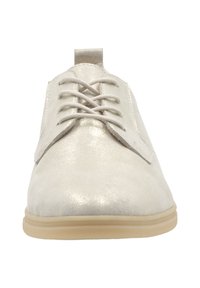 Chaussures à lacets synthétiques de couleur claire avec une texture brillante, bout arrondi et semelle en caoutchouc à profil bas. Elles présentent des lacets plats et une languette à l'arrière.