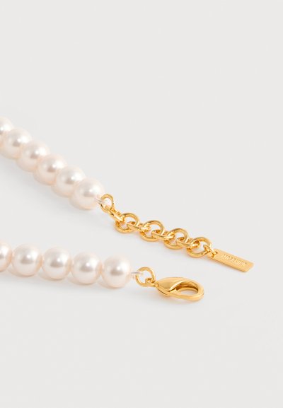 Collier de perles composé de perles blanches rondes, d'accents en chaîne dorée et d'un fermoir homard en or. Comprend une étiquette avec le nom de la marque.