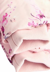 Jachetă puf cu imprimeu floral de culoare roz deschis, realizată dintr-un material moale cu un finisaj neted și manșete din tricot cu nervuri. Accente florale în nuanțe de roz mai închis.