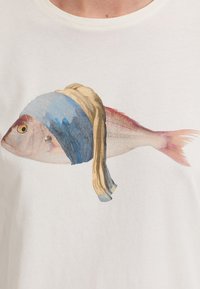 Cotton t-shirt featuring a printed illustration of a fish with a blue headscarf and blonde fabric draped, set on a white background.