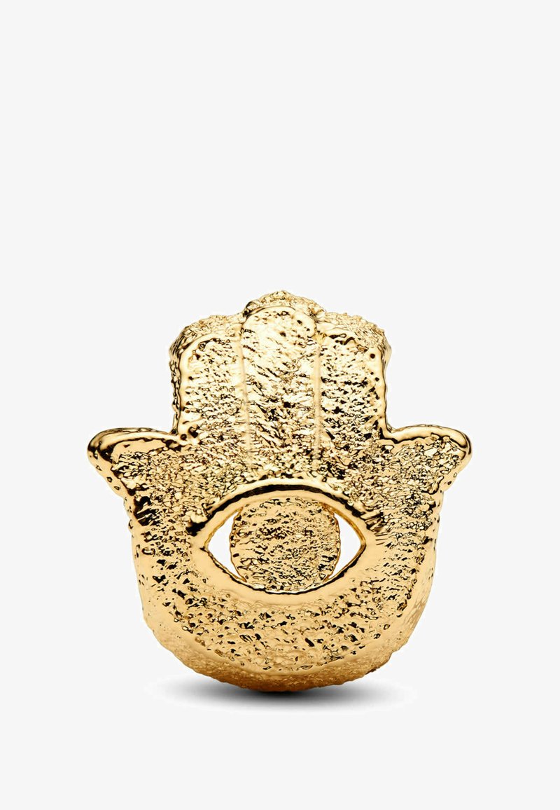 Talismano dorato a forma di mano con superficie testurizzata, caratterizzato da un motivo centrale a occhio. Il design è intricato, mettendo in risalto i dettagli decorativi.