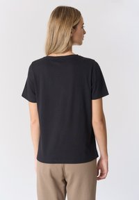 T-shirt in cotone nero con maniche corte, scollo tondo e vestibilità comoda, mostrata da dietro su uno sfondo bianco semplice.