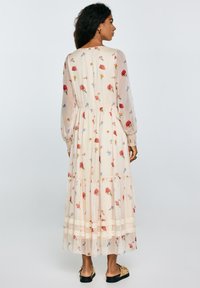 Maxi-jurk met bloemenprint in lichtcrème, voorzien van lange doorzichtige mouwen, gelaagd ontwerp en kantafwerking aan de zoom. Zachte, vloeiende stof.