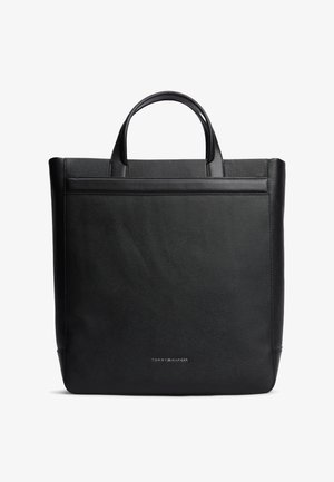 Sort læder tote taske med korte håndtag og lille Tommy Hilfiger-logo centreret nær bunden foran.