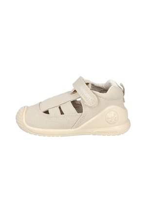 Sandalia beige para niño pequeño con puntera cerrada, malla transpirable, correa ajustable de Velcro y suela de goma diseñada para soporte flexible y comodidad.
