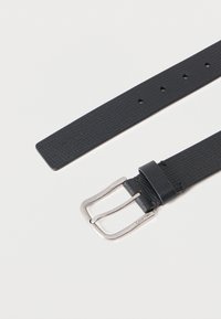 Μαύρη δερμάτινη ζώνη με υφή, με επάργυρη ορθογώνια αγκράφα, που διαθέτει πολλαπλές τρύπες και λουράκι που στενεύει προς το τέλος.