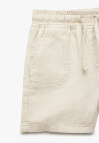 Pantalones cortos de lino beige con cintura elástica, cordón de ajuste y detalle de costura en el bolsillo frontal, mostrados sobre un fondo blanco.