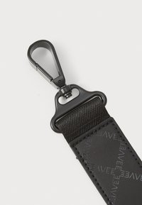Black nylon strap with a textured surface, featuring a durable metal clip and embossed logo detail. Modern and functional design.