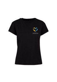 Melnas kokvilnas T-krekls ar daudzkrāsainu sirdi grafikā, kas ir zila un dzelta, ar vārdu "УКРАЇНА" drukātu zemāk baltā krāsā.