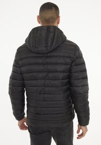 Chaqueta negra acolchada con capucha, con secciones acolchadas horizontales. El material parece suave con un acabado brillante, adecuado para el clima frío.