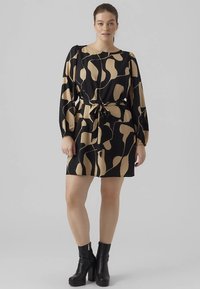 Rochie neagră cu modele abstracte mari bej, mâneci bufante și talie cu cordon. Asortată cu ghete negre cu platformă și gleznă înaltă.