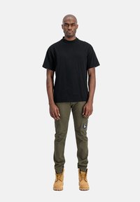 Sort bomulds T-shirt, slim-fit olivenfarvede cargo bukser med sidelommer og brune støvler med snørebånd. Enkel, funktionel design med holdbare materialer.