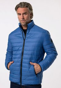 Izolovaná modrá puffer bunda s horizontálním prošíváním, vysokým límcem, černým zipem a bočními kapsami. Vyrobena z lesklého, hladkého materiálu.