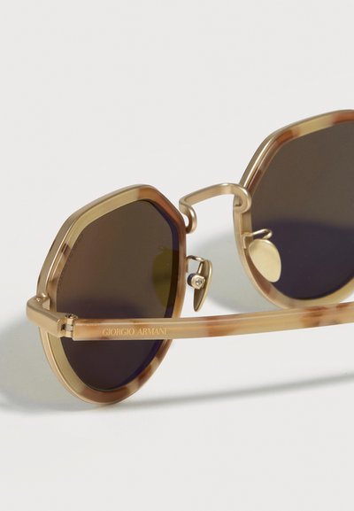 Οκταγωνικά γυαλιά ηλίου σε χρυσό τόνο με σκούρους φακούς και διαφανείς καφέ βραχίονες με ανάγλυφο το λογότυπο Giorgio Armani.