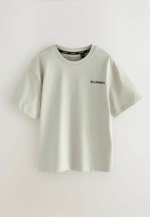 Svetlo šedé tričko s krátkym rukávom vyrobené z mäkkej bavlny, s okrúhlym výstrihom a malým čiernym textovým logom na hrudníku.