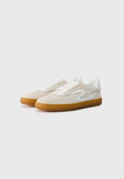 Baskets basses en suède beige et cuir blanc, dotées d'une semelle en caoutchouc gomme, de lacets et d'un accent de logo blanc courbé.