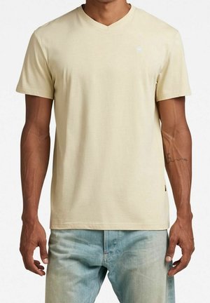 Lys beige v-hals t-shirt lavet af blødt stof. Korte ærmer, almindelig pasform, med et lille logo på brystet og diskrete syninger.
