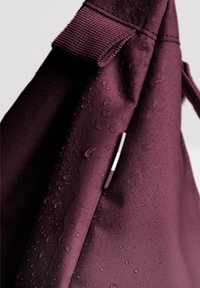 Borsa impermeabile bordeaux con una superficie testurizzata, caratterizzata da gocce d'acqua e un dettaglio in accento argento sul lato.