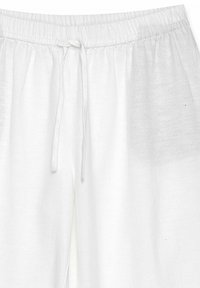 Witte linnen broek met een elastische tailleband en verstelbare koordjes. De stof lijkt lichtgewicht en heeft een lichte textuur.