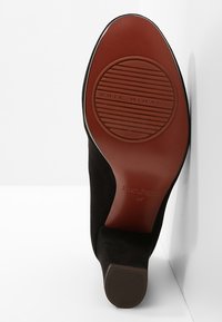 Vue de la semelle d'une chaussure à talon noir avec une semelle extérieure en caoutchouc marron, affichant la marque "CHIE MIHARA" et la taille 37.