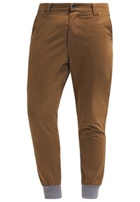 Pantaloni marroni slim-fit con una texture liscia, caratterizzati da un polsino grigio alla caviglia, una tasca frontale e una chiusura con bottone.