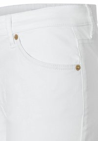 White denim jeans featuring a slim fit, gold hardware on the pockets, and subtle stitching details along the edges.