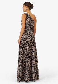 Abito nero a spalla unica con motivo floreale in beige. Corpino aderente con gonna fluente, tessuto texturizzato, silhouette elegante e lunga.