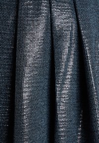 Ciemnoniebieska tkanina o teksturowanej, lekko błyszczącej powierzchni, z plisami, które nadają strukturę, zwiększając głębię wizualną.