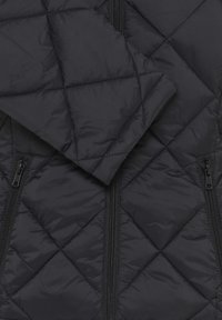 Veste noire matelassée avec un devant zippé, deux poches zippées et une finition douce et brillante. Le design comprend un rembourrage en forme de diamants.