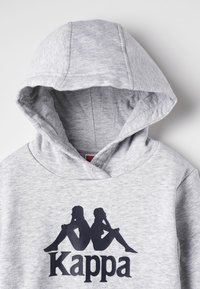 Felpa grigia con cappuccio caratterizzata da un grande logo Kappa nero con due silhouette sedute. Il tessuto sembra morbido, con una superficie liscia e un design del cappuccio classico.