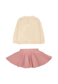 Maglione lavorato a maglia di un beige chiaro con scollo a coste, dotato di una chiusura con bottoni sul retro. Gonna plissettata rosa con vita elasticizzata.