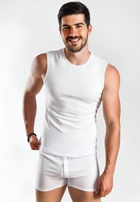 Witte mouwloze shirt gemaakt van glad, rekbaar stof, gecombineerd met witte strakke boxers, die een slanke pasvorm en minimaal ontwerp benadrukken.