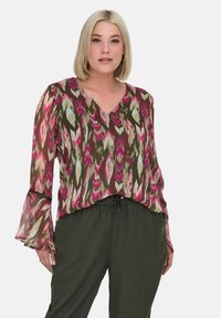 Blusa a maniche lunghe con scollo a V in un motivo multicolore che presenta tonalità di rosa, verde e crema, con maniche trasparenti e una vestibilità ampia.